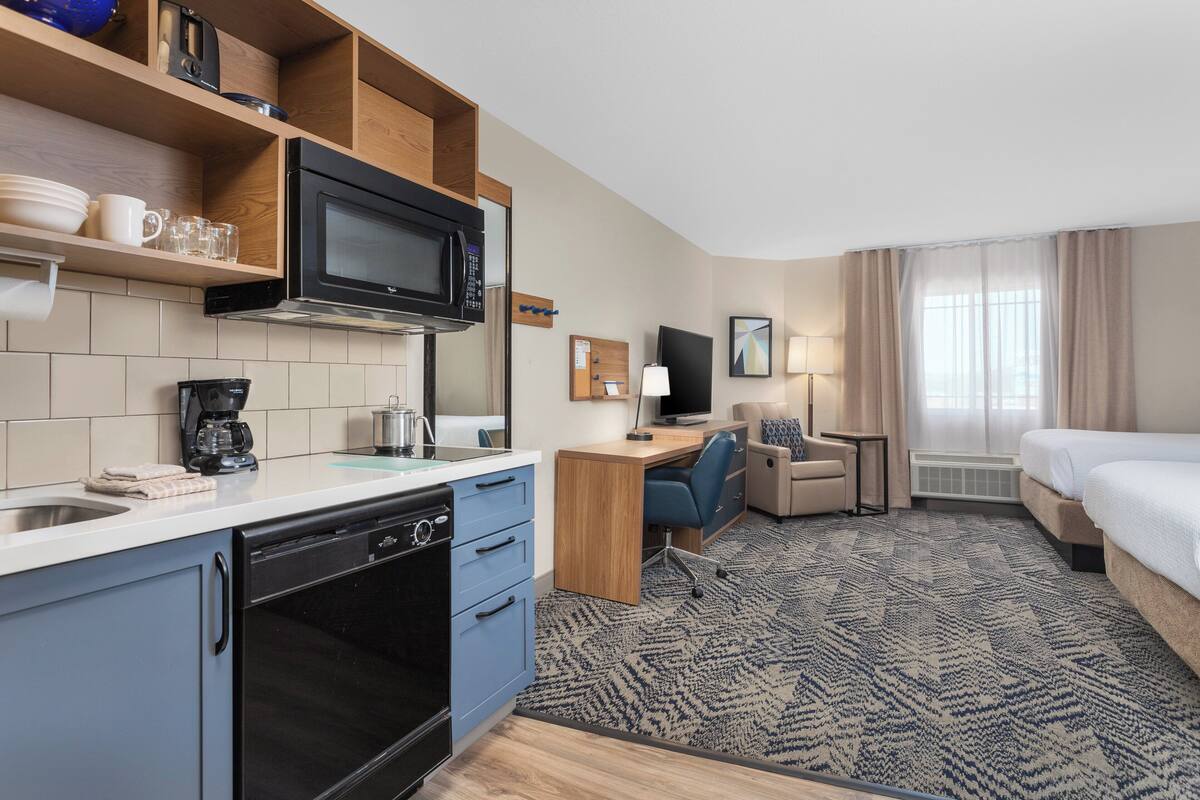 Une chambre d’hôtel équipée d’une kitchenette, d’un lit, d’un bureau et d’une télévision.