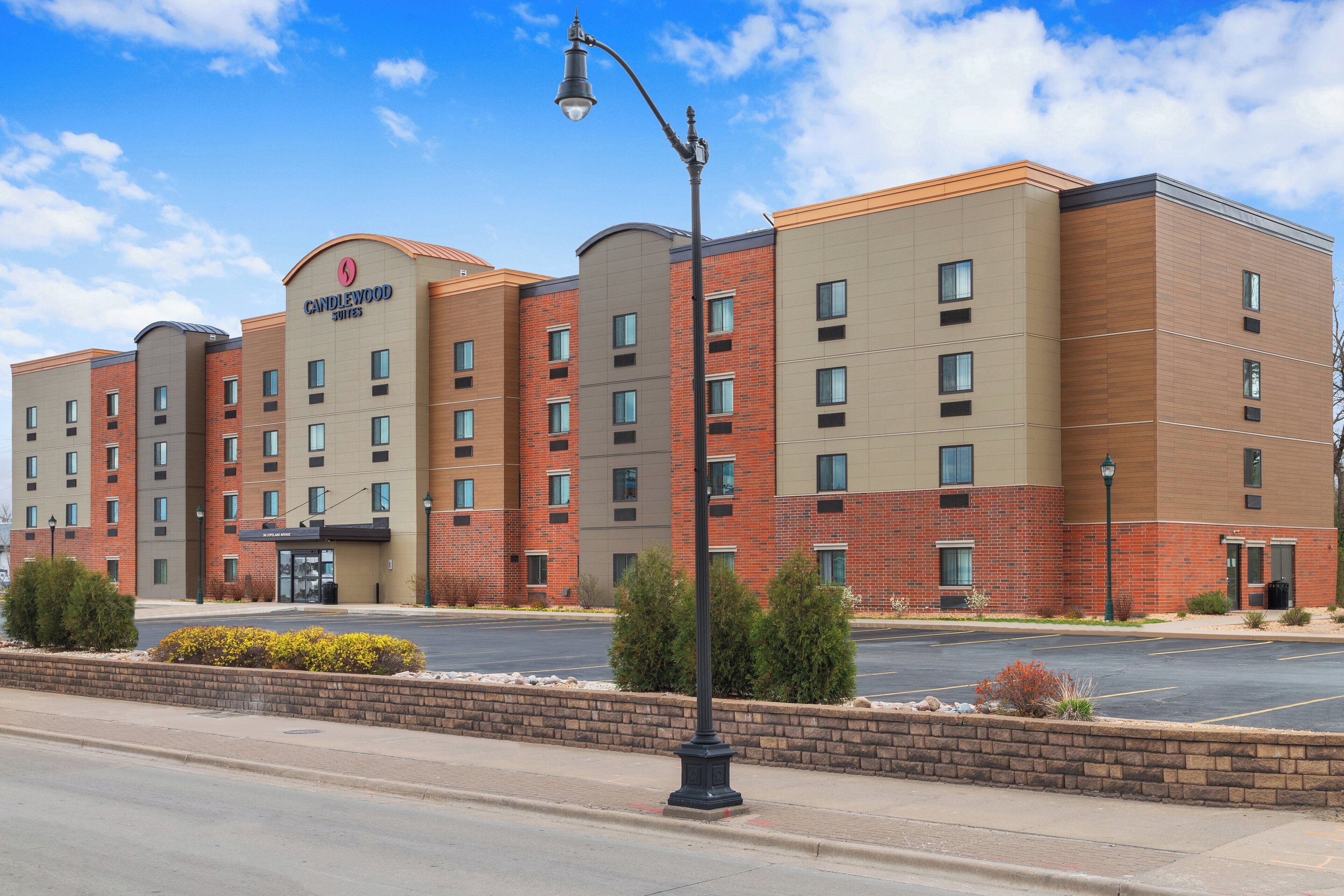 A multi-story hotel with a brick facade, a prominent entrance, and a parking lot in front.