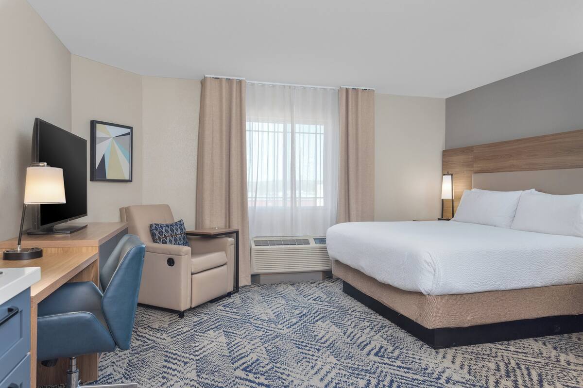 Une chambre d’hôtel équipée d’un lit, d’un bureau, d’une chaise, d’une télévision et d’un appareil de climatisation.