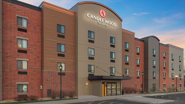 Ett hotell med flera våningar, med en tydlig skylt som visar namnet ”Candlewood Suites”, och som har en fasad av tegel samt en modern design.
