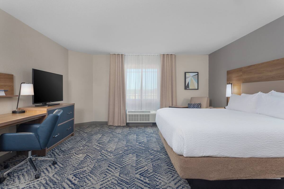 Une chambre d’hôtel équipée d’un lit, d’un bureau, d’une chaise, d’une télévision et d’un appareil de climatisation.
