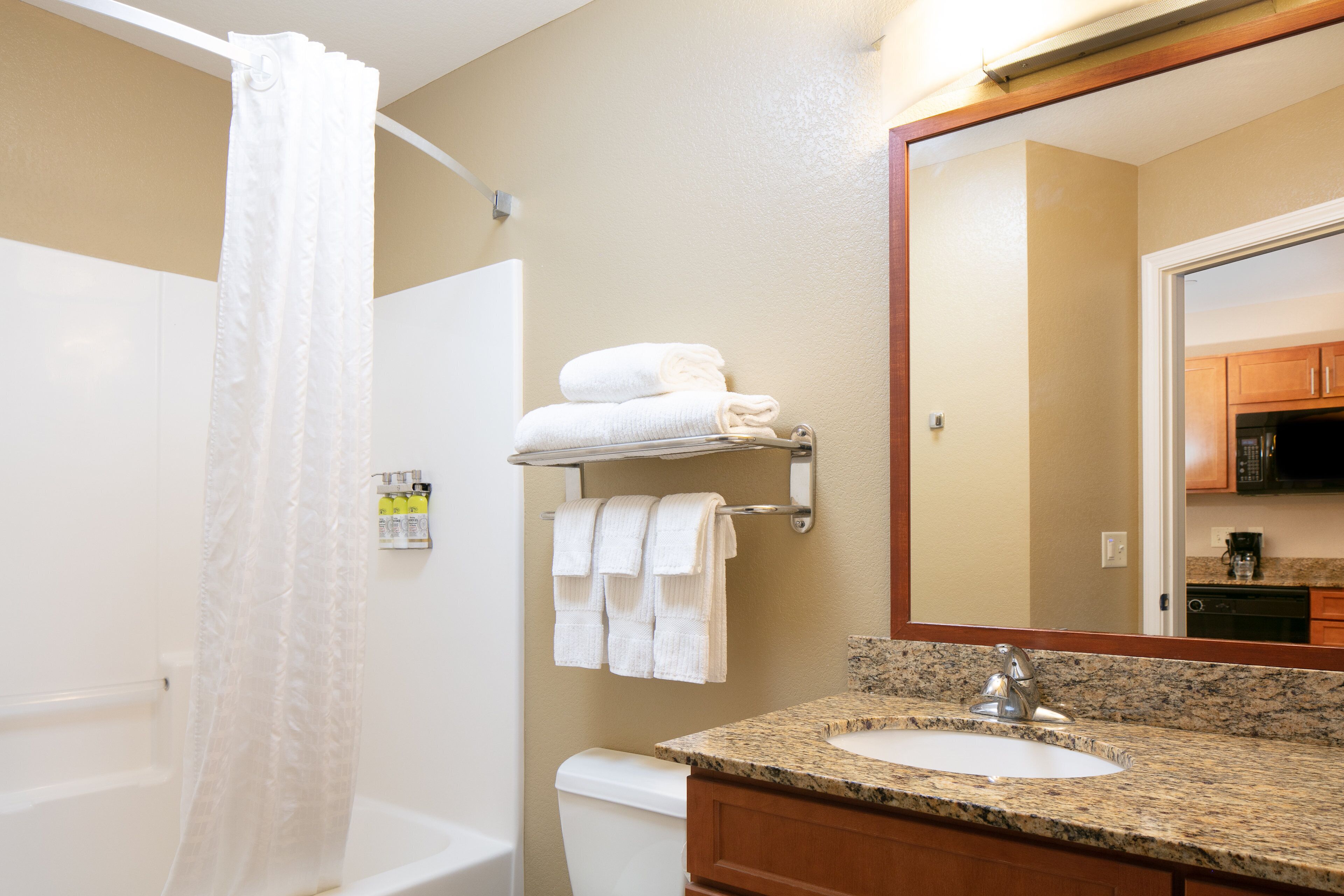 A bathroom with a shower, toilet, sink, and a mirror.