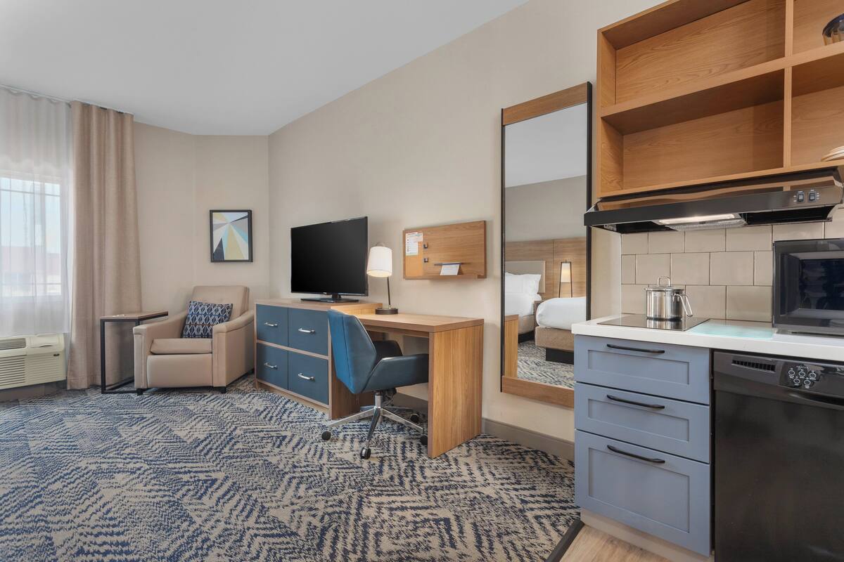 Une chambre d’hôtel équipée d’un bureau, d’une chaise, d’une télévision et d’une kitchenette.