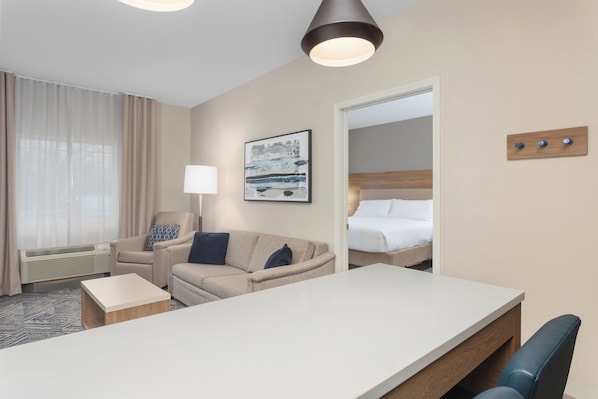 A hotel room with a bed, a sofa, a desk, and a lamp.