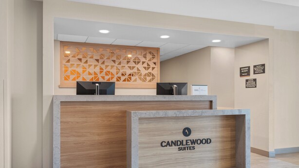 Un comptoir d’accueil avec un panneau en bois et une enseigne indiquant « CANDLEWOOD SUITES ».