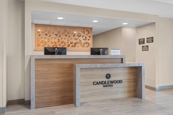 A reception desk with a wooden panel and a sign that reads "CANDLEWOOD SUITES". - Candlewood Suites La Crosse N by IHG (La Crosse)