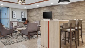 Un salon moderne avec un mur d’accent en bois, un téléviseur à écran plat et un coin bar équipé de tabourets.