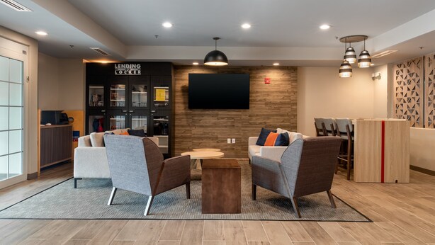 A modern lobby with seating, a coffee machine, and a television.