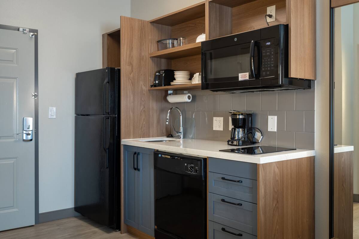 Una cocina moderna con un refrigerador negro, un microondas integrado y un lavavajillas.