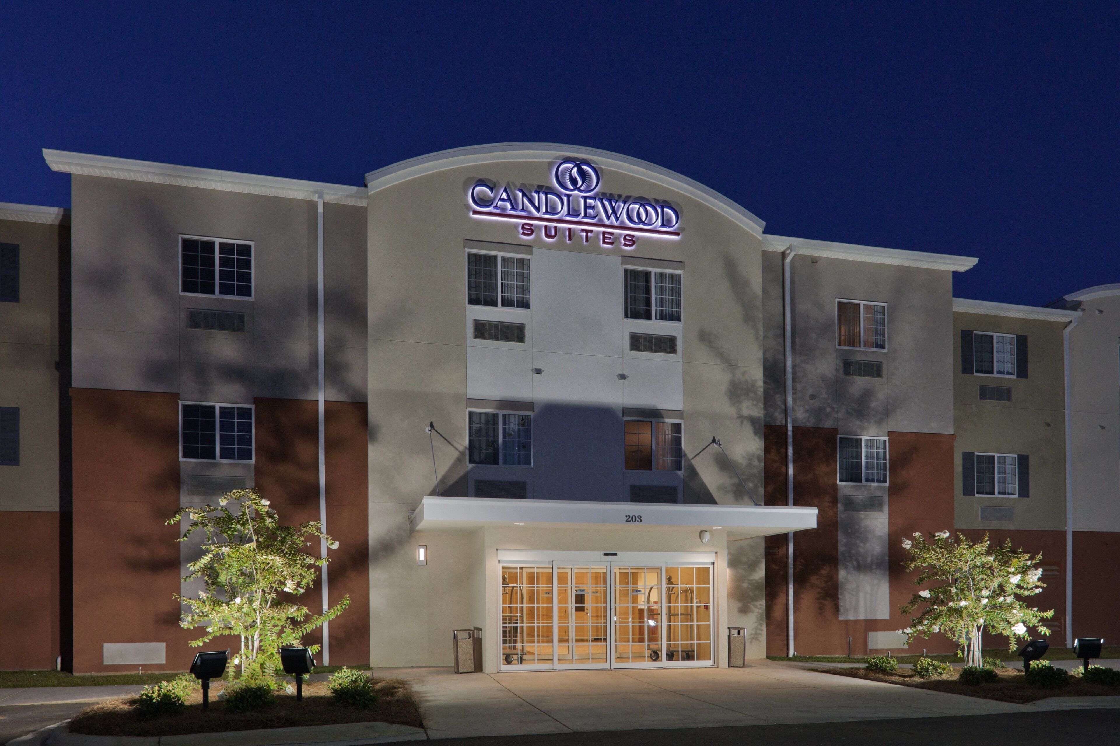 A hotel with a modern facade, a prominent entrance with glass doors, and a sign indicating it is a Candlewood Suites.