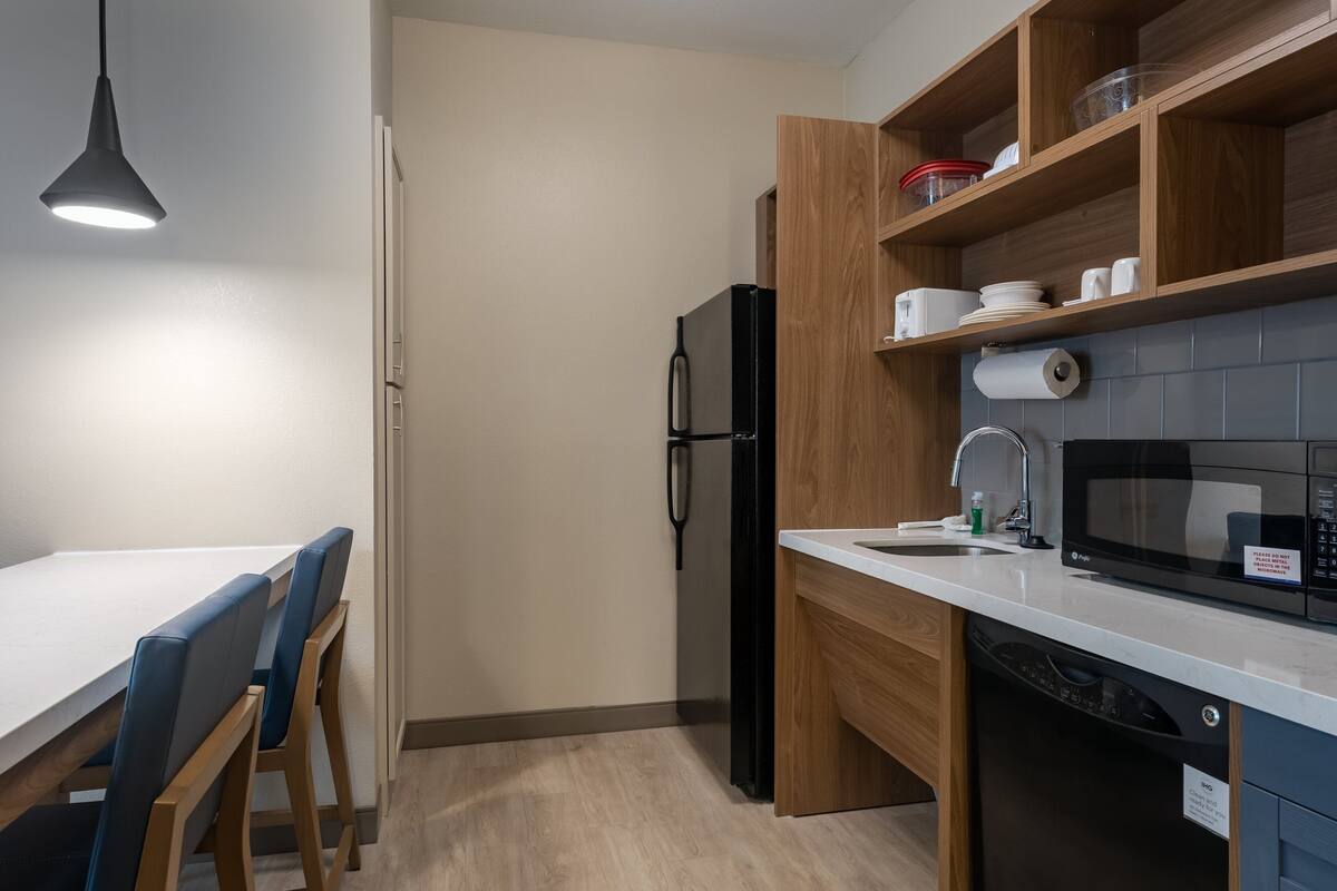 Una cocina moderna con refrigerador, microondas y armarios de madera.