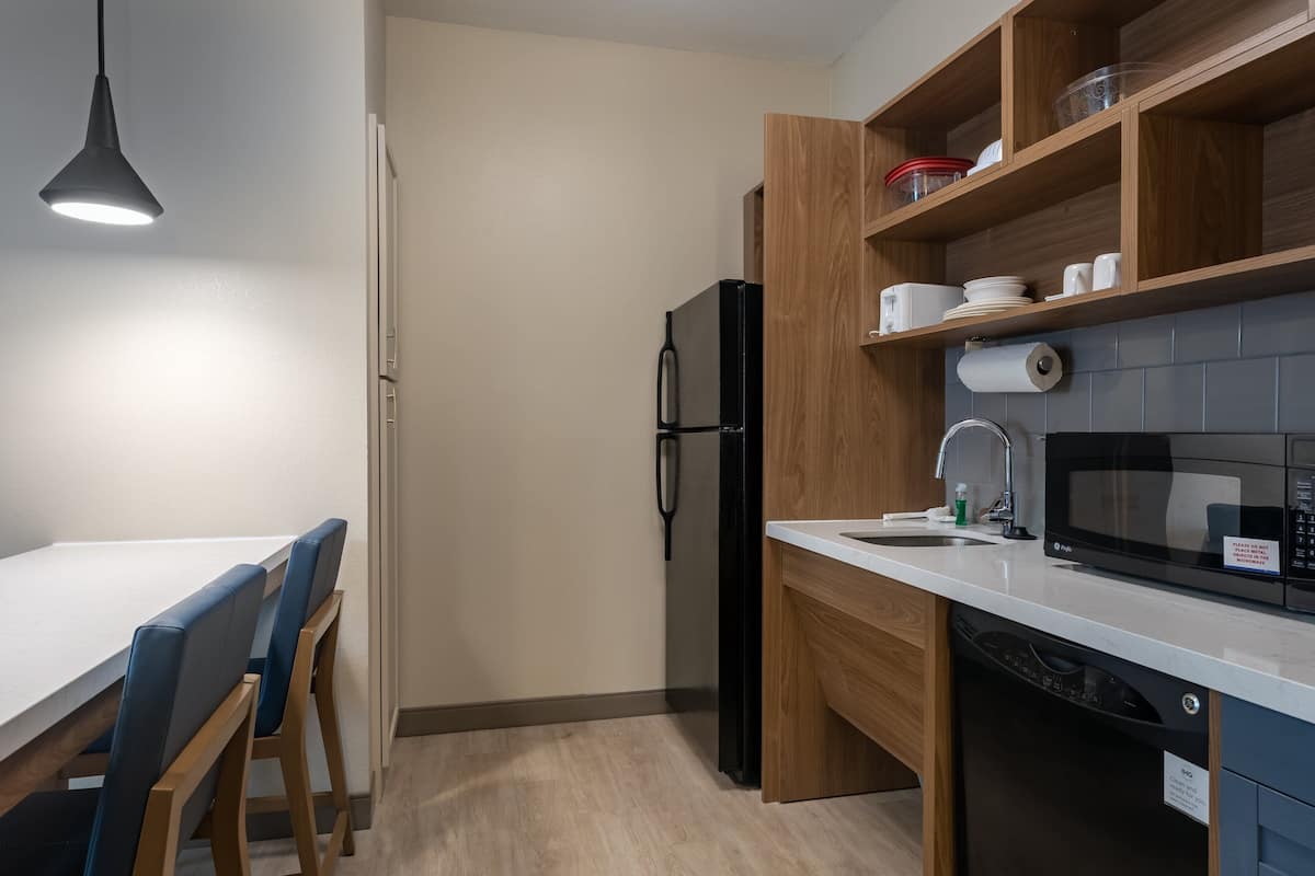 Une cuisine moderne équipée d’un réfrigérateur, d’un four à micro-ondes et de meubles de rangement en bois.
