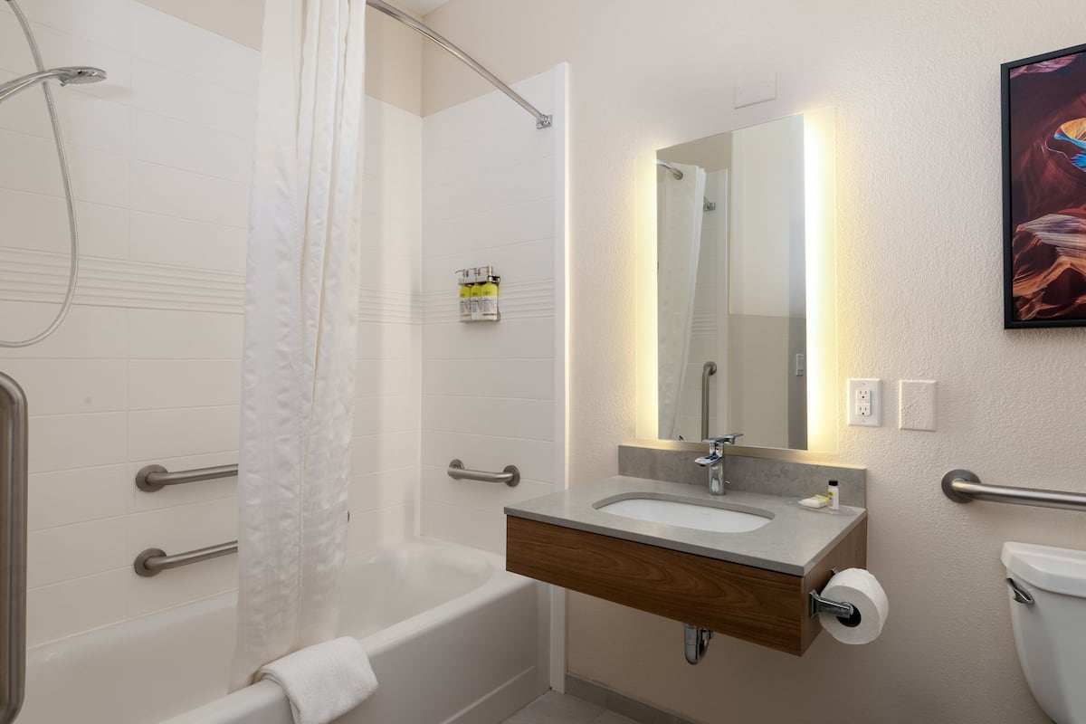 Un baño moderno con bañera, lavamanos con espejo e inodoro.