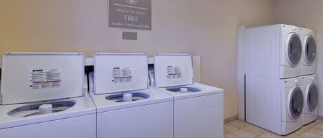 A laundry area with three Kenmore washers and dryers, a sign indicating free washer and dryer use, and a wall-mounted sign above.