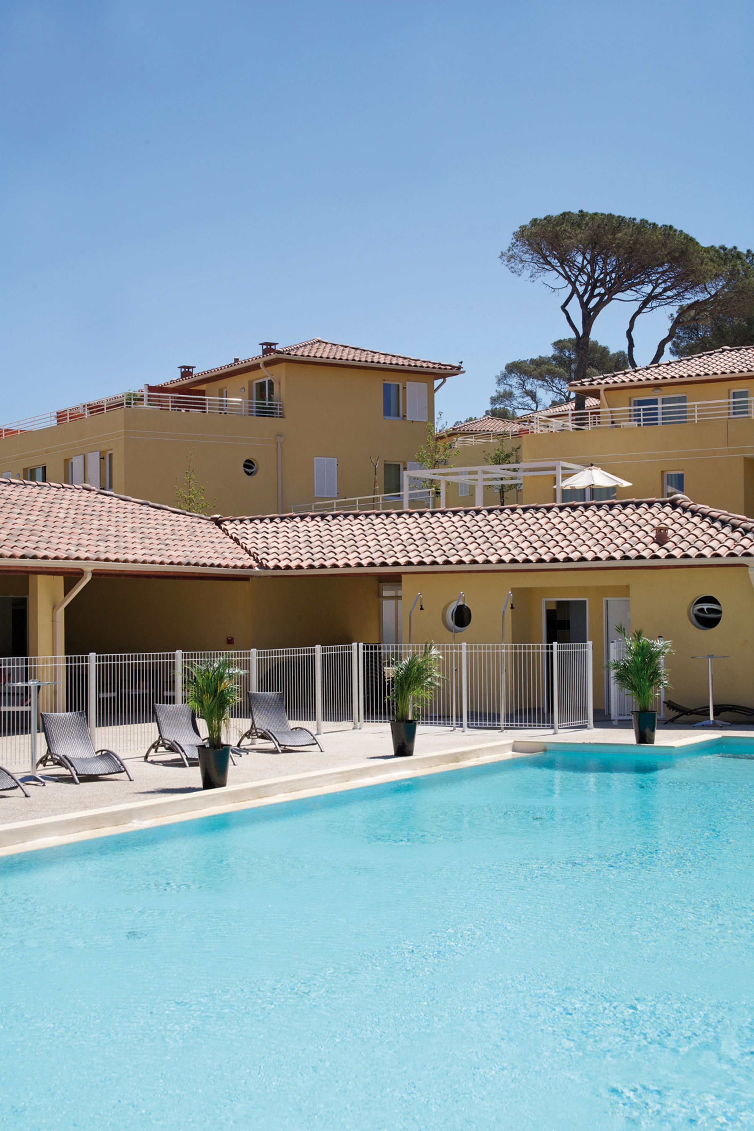 Área de piscina com espreguiçadeiras e um edifício com telhado telhado.