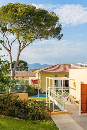 Een resort met een zwembad, buitenterras en een grote boom.