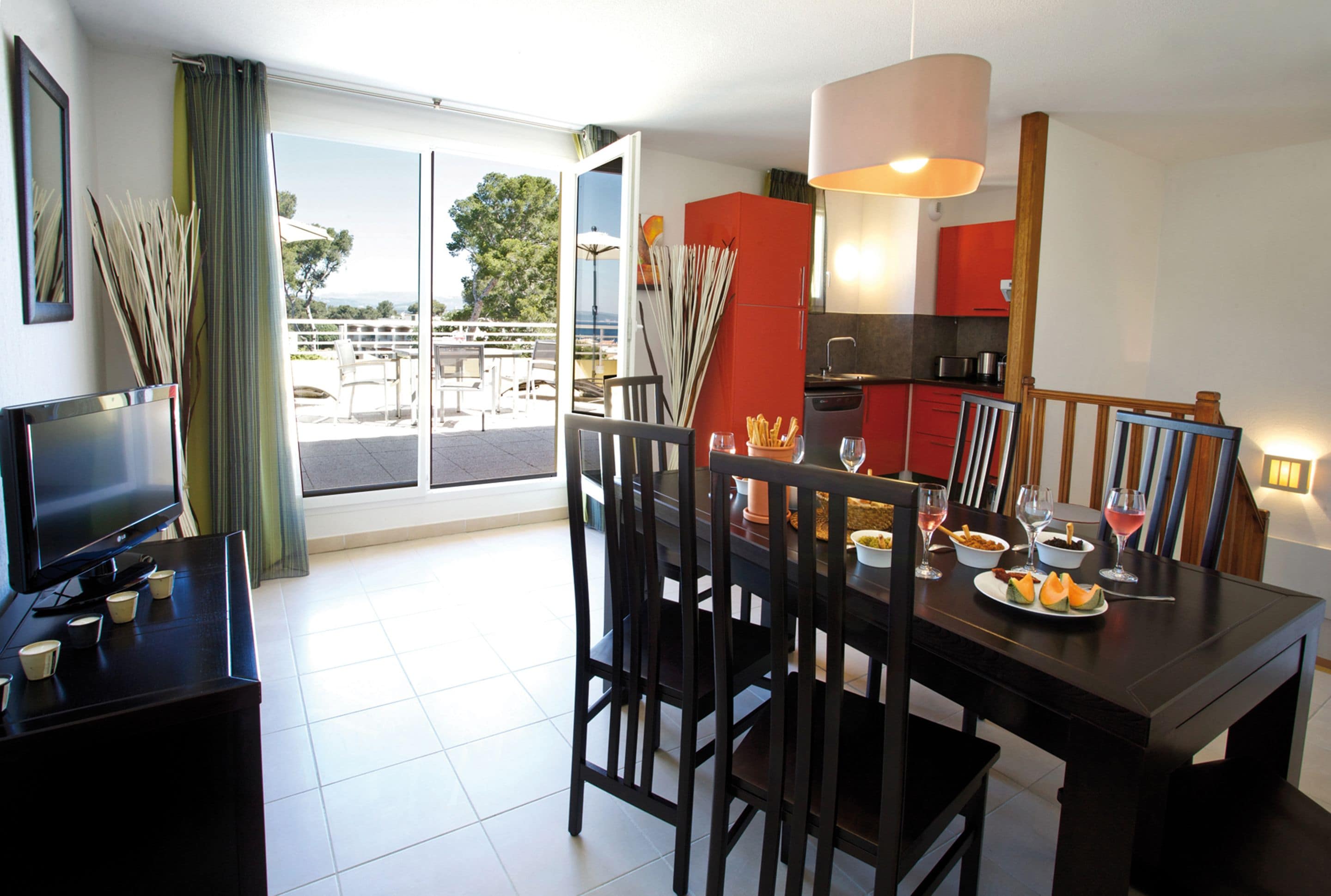 A dining area with a table set for four, a television, and a view of the outdoors.
