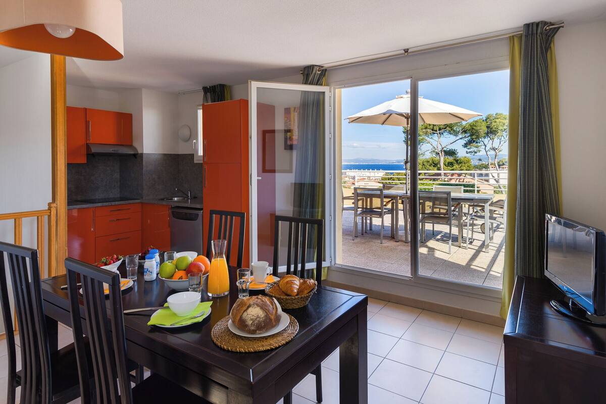 A dining area with a table set for breakfast, a TV, and a view of the outdoors.