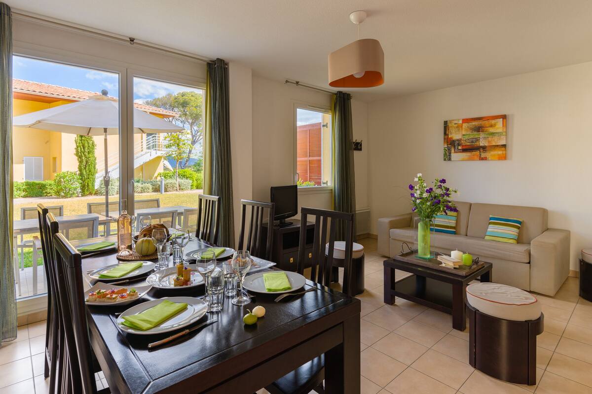 A dining area with a table set for four, a sofa, a coffee table, and a TV.