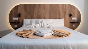 A neatly made bed with white linens, a wooden headboard, and two wall-mounted light switches. - Hotel Aloe Emira NKC (Nouakchott)