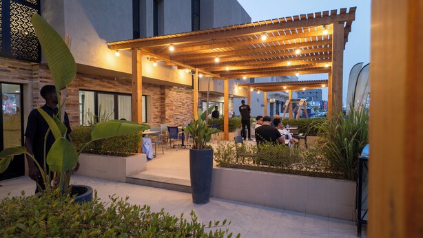 An outdoor patio area with a wooden pergola, seating arrangements, and potted plants. - Hotel Aloe Emira NKC (Nouakchott)