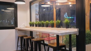 A bar area with a long counter, several stools, and potted plants. - Hotel Aloe Emira NKC (Nouakchott)