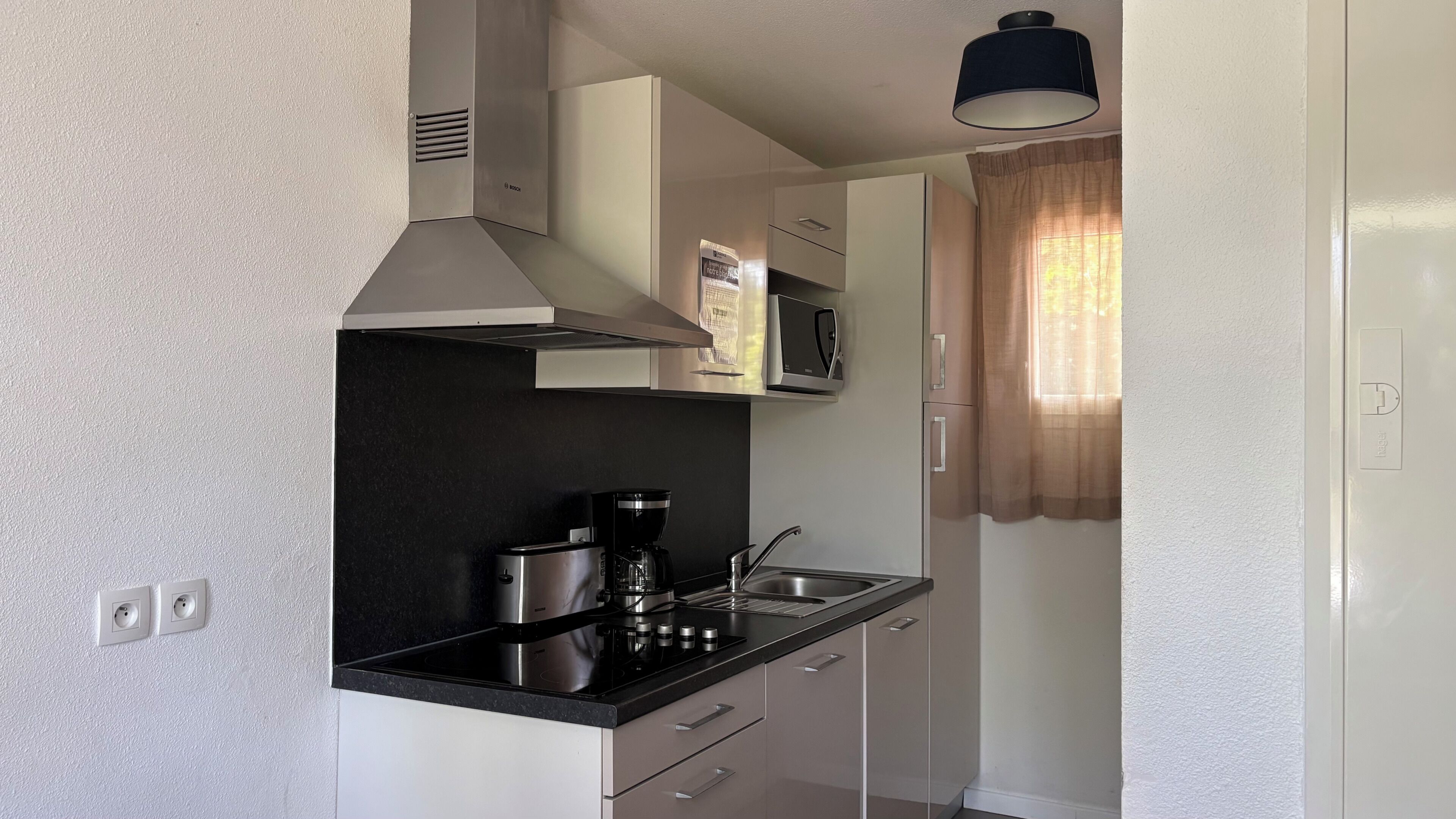 A compact kitchen with a black countertop, stainless steel appliances, and a microwave.