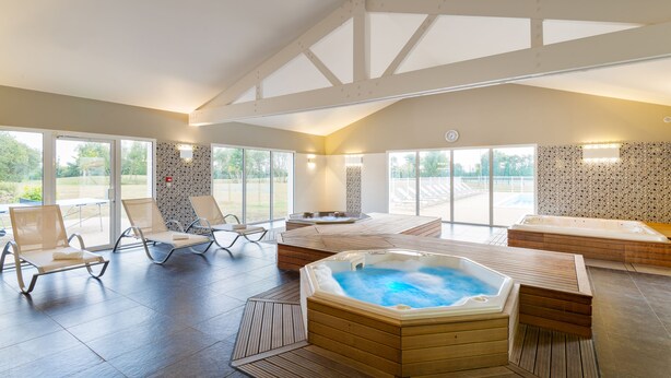 Un área de spa con jacuzzi, sillones de descanso y vistas al exterior.