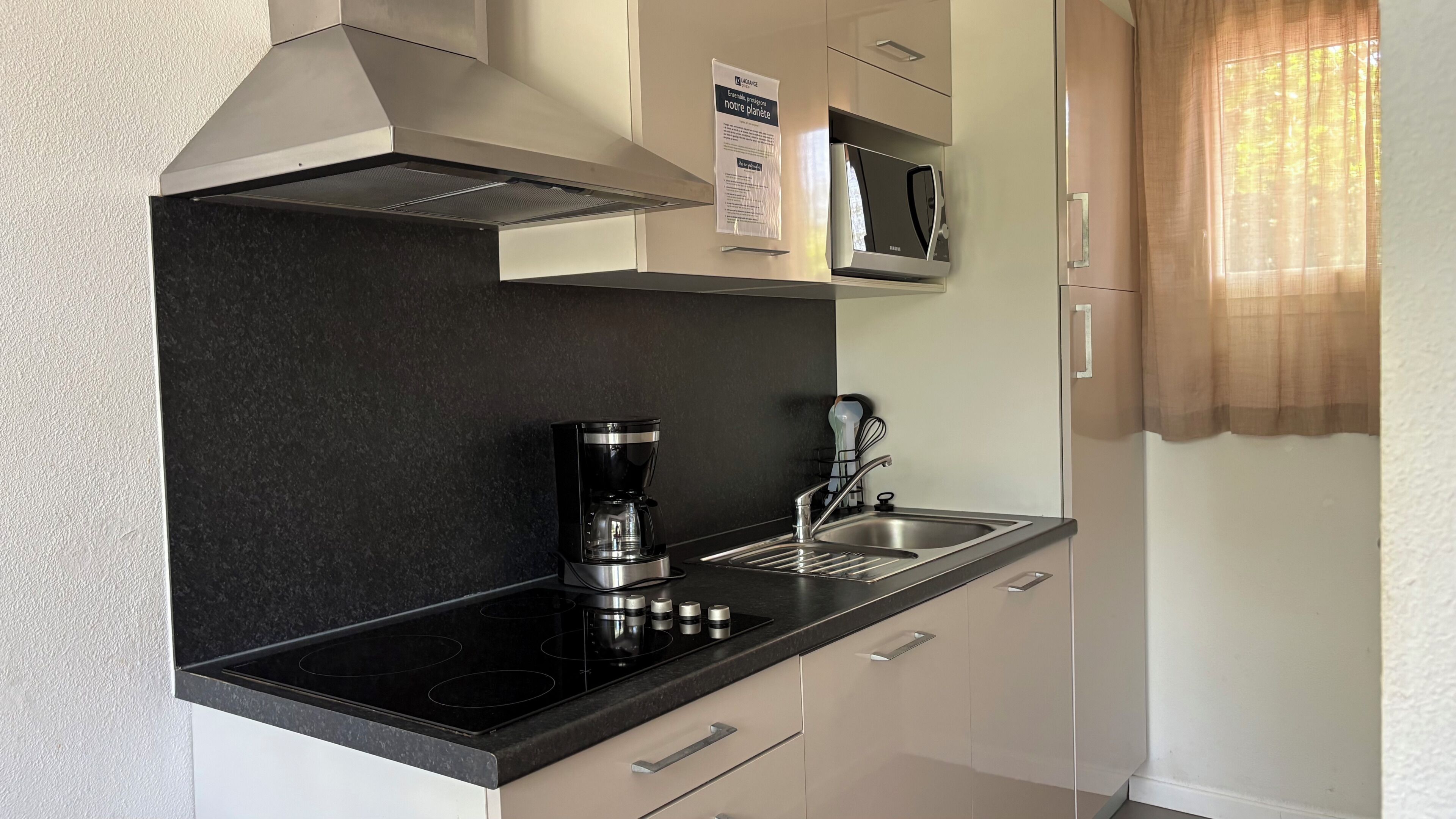 Una cucina moderna con piano di lavoro nero, elettrodomestici in acciaio inossidabile e forno a microonde.