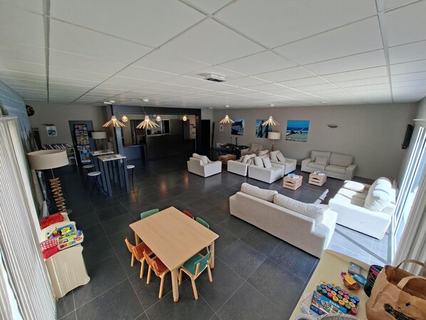A spacious living area with a dining table, sofas, and a kitchen in the background.