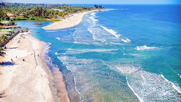 A beach with clear blue waters, a sandy shore, and a few people.