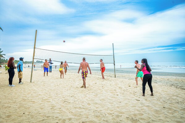 A beach volleyball game with players in various swimwear.