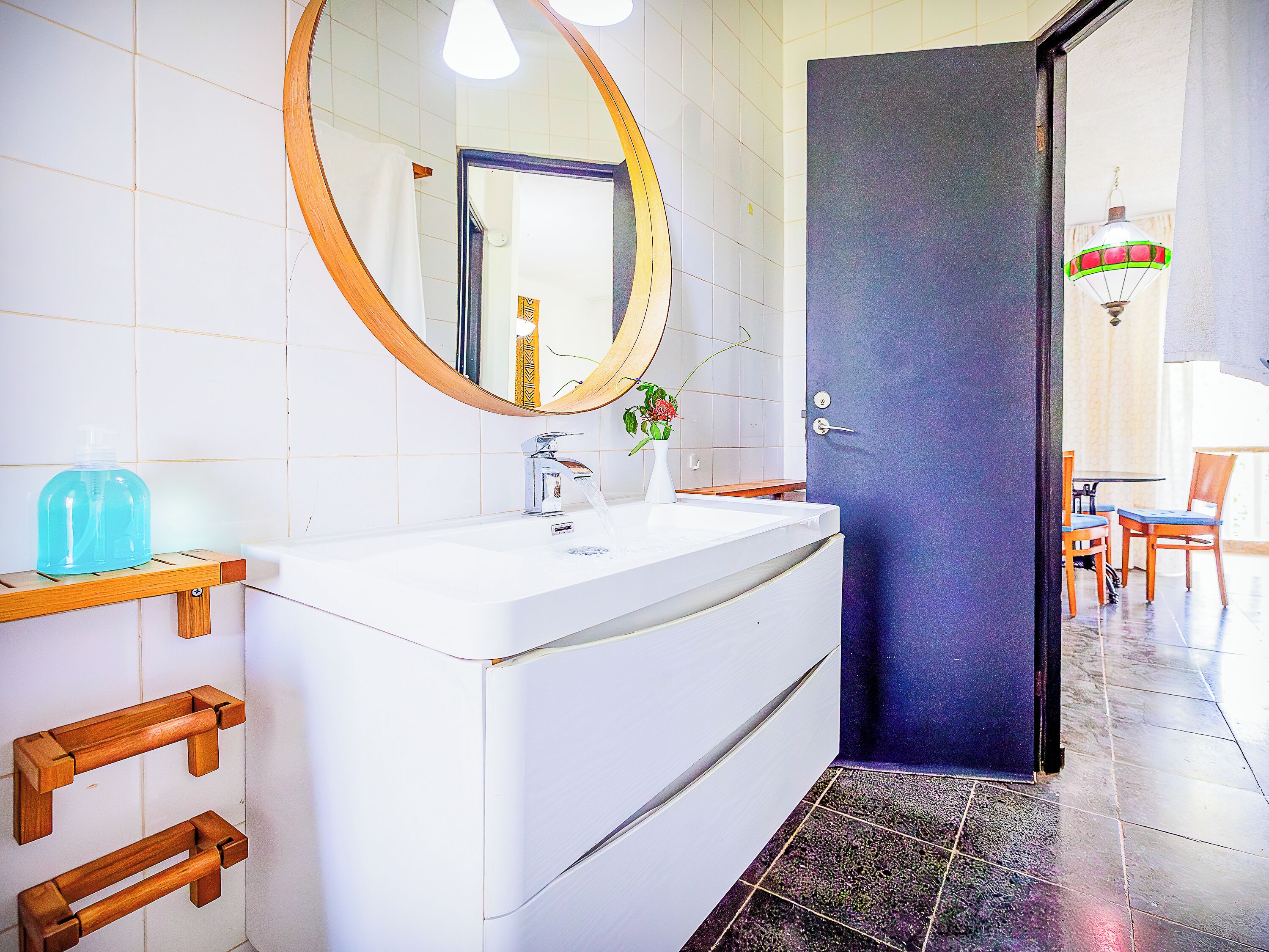 A bathroom with a white sink, a mirror, and a blue door.