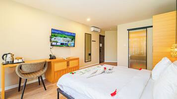 Una habitación de hotel con cama, escritorio, silla, televisor y armario de madera.