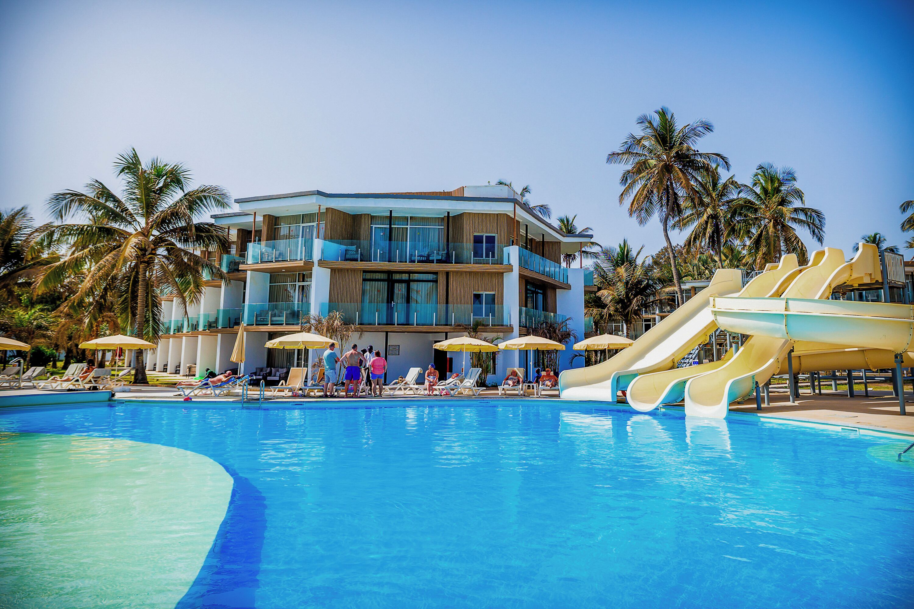 A swimming pool with slides, lounge chairs, and umbrellas.