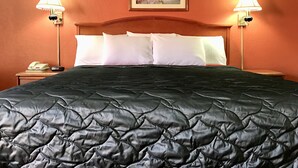 A hotel room with a bed, two bedside lamps, a framed picture on the wall, and a telephone on the nightstand. - Best Budget Inn - Abilene (Abilene)