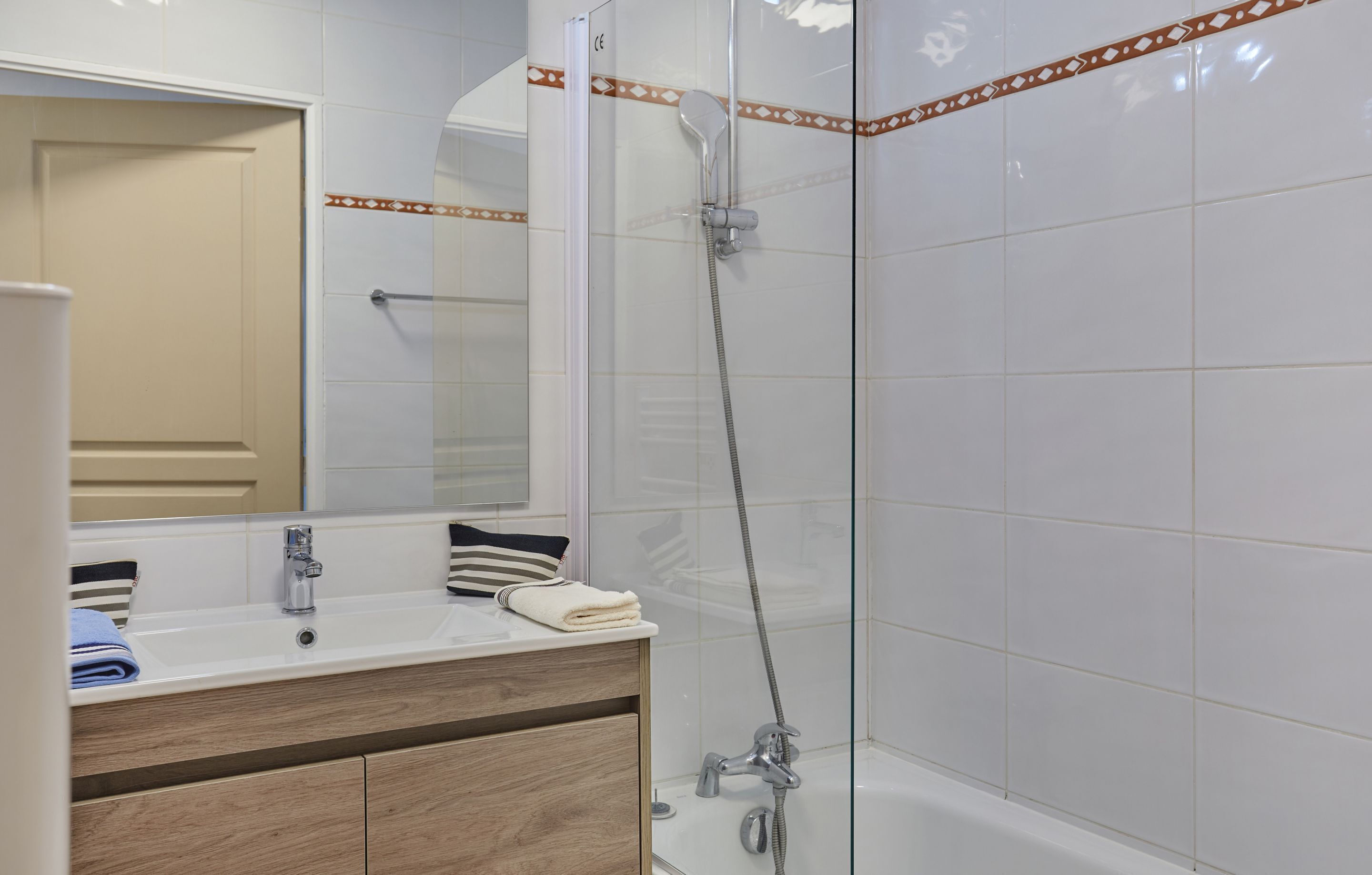 A bathroom with a white sink, mirror, and shower.