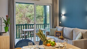 Habitación con una mesa de comedor dispuesta para dos personas, un sofá y vistas al exterior.