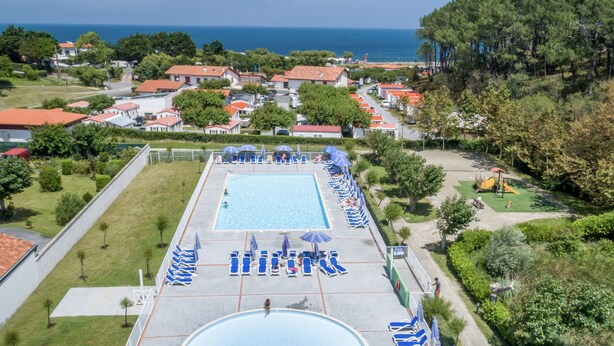Un complejo turístico con una amplia piscina, tumbonas y vistas al mar.