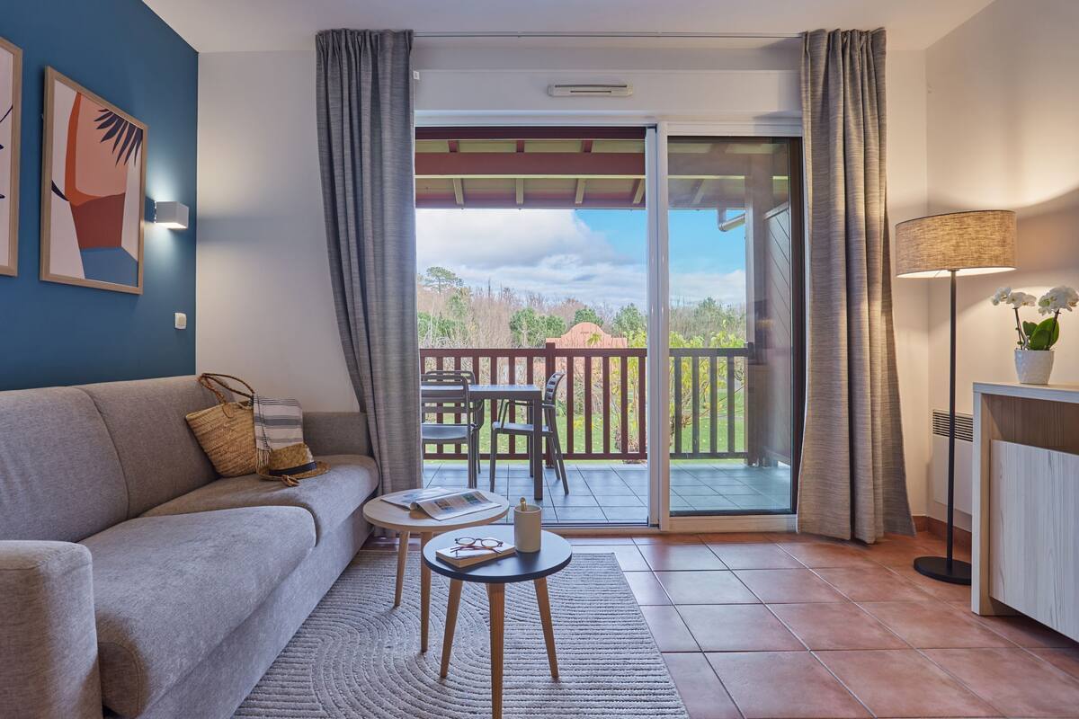 Ein Wohnzimmer mit einer Couch, einem kleinen Tisch und einem Balkon mit Blick ins Freie.