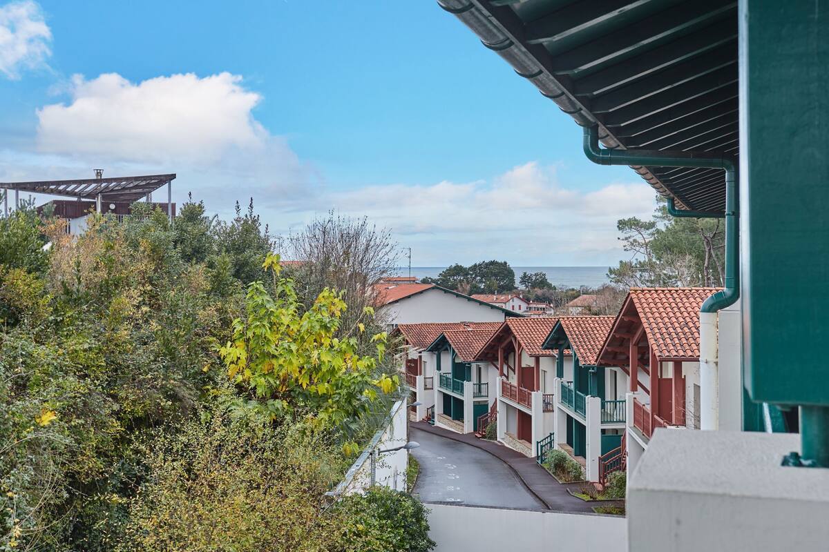 Ein Küstenhotel mit Gebäuden mit Terrakotta-Dächern, einem gepflasterten Weg und Blick aufs Meer.