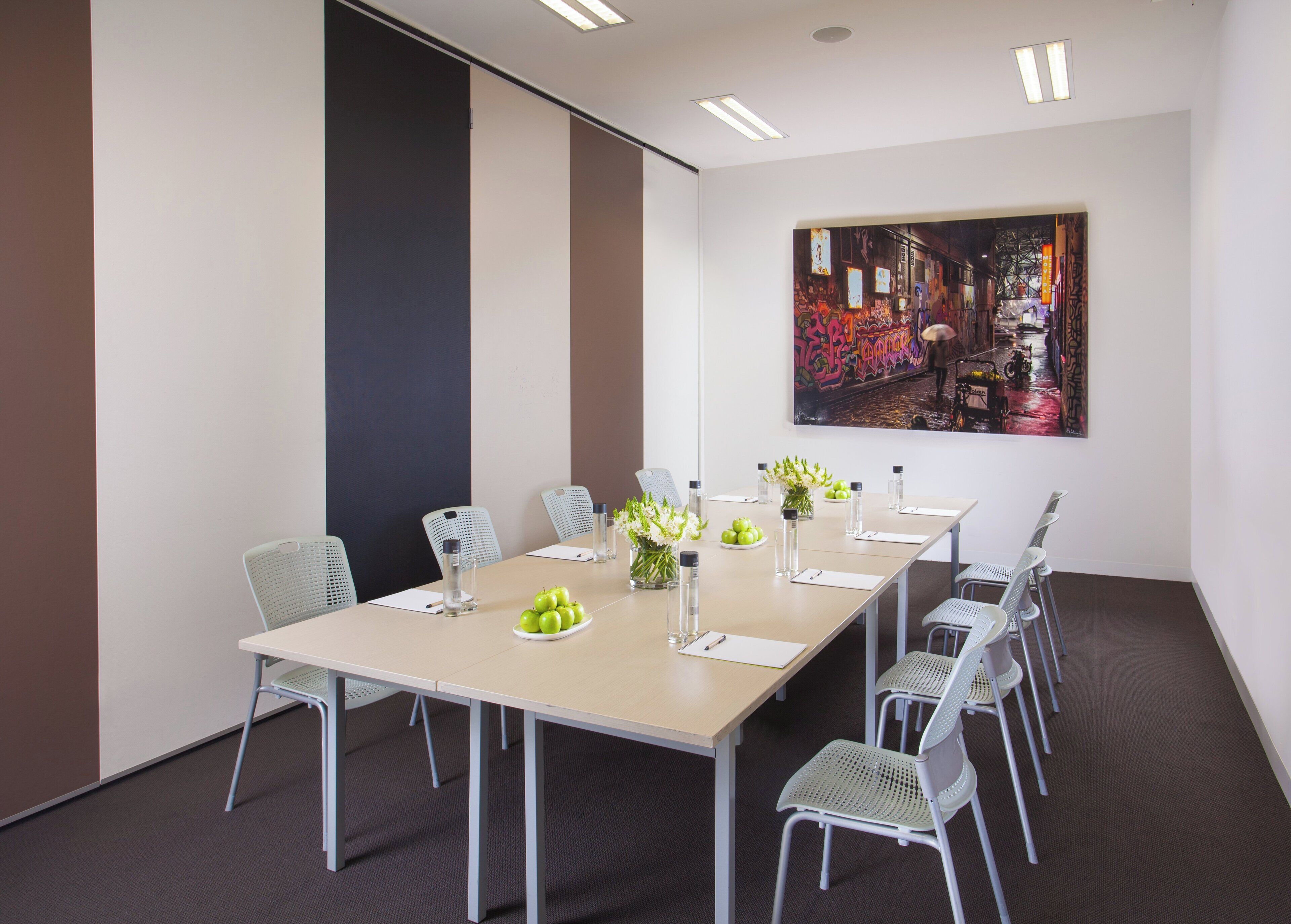 A conference room with a long table, chairs, a painting, and a water dispenser.