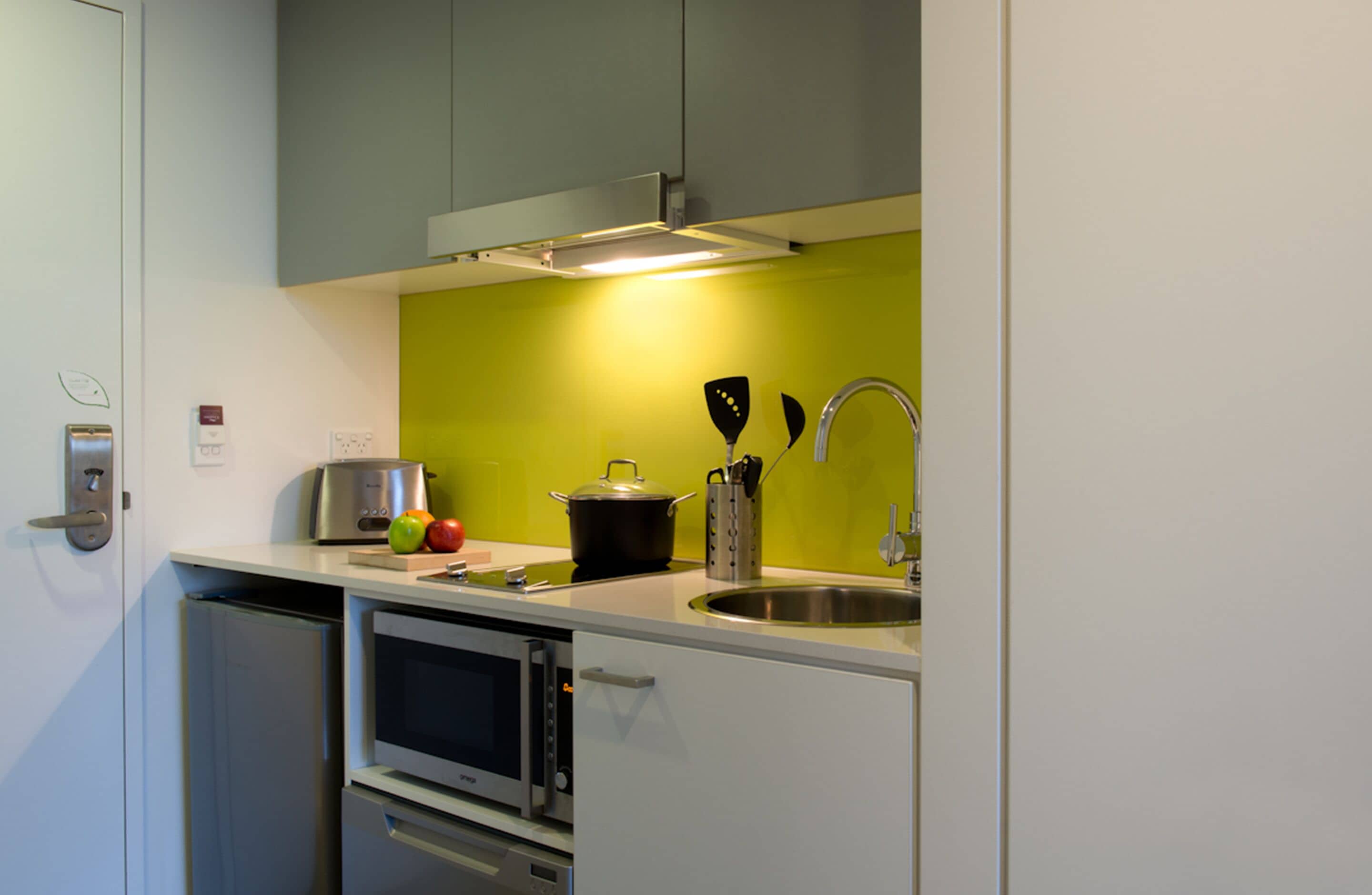 A compact kitchen with a microwave, oven, and a sink.