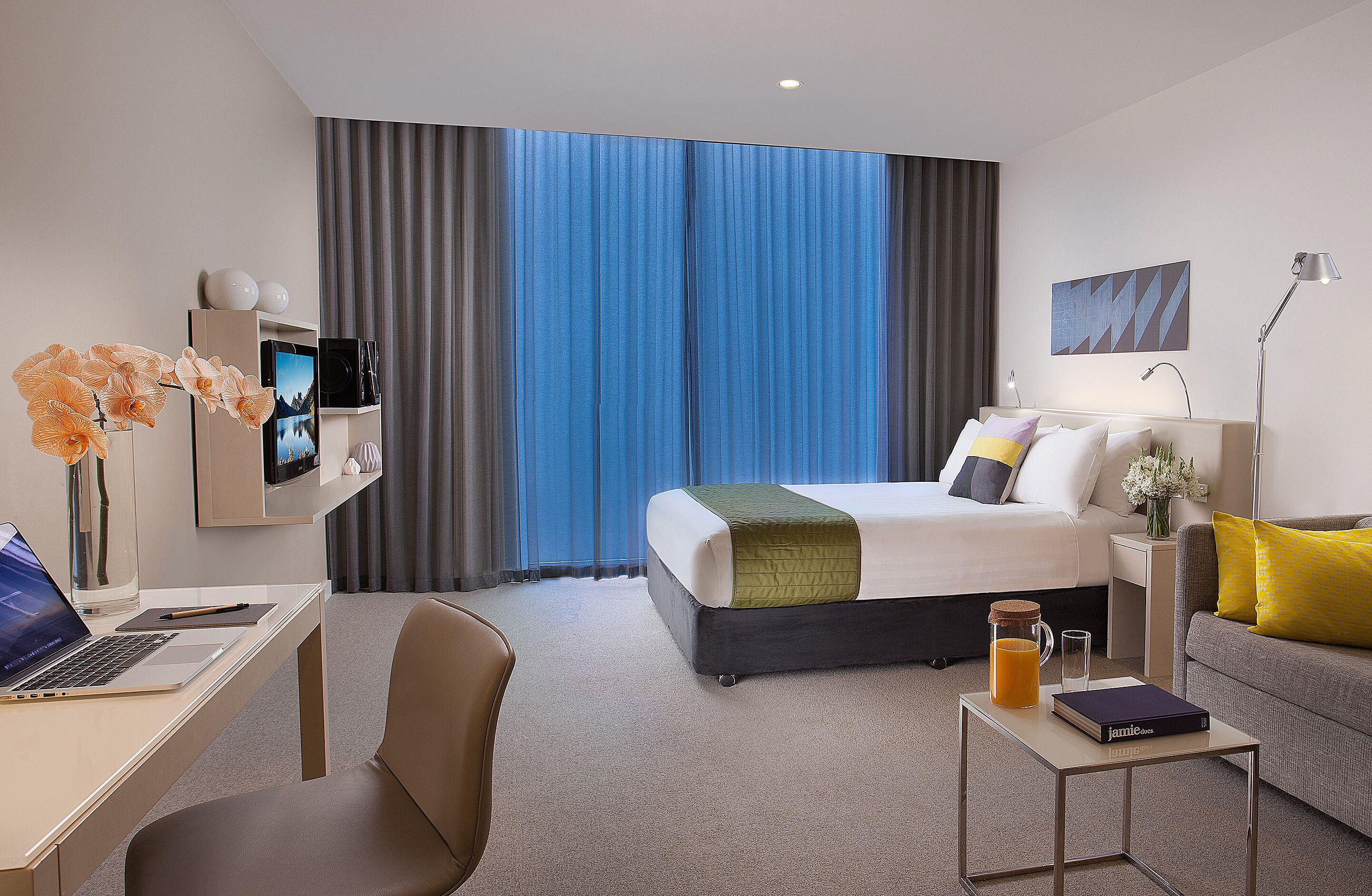 Una habitación de hotel moderna con cama, escritorio y zona de estar.