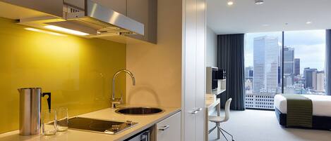 Habitación de hotel moderna con cocina, cama y vistas a la ciudad.