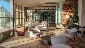 A spacious lobby with a modern design, featuring a seating area with sofas and armchairs, a large potted plant, and a patterned wall. - Real Marina Hotel & Spa (Olhao)
