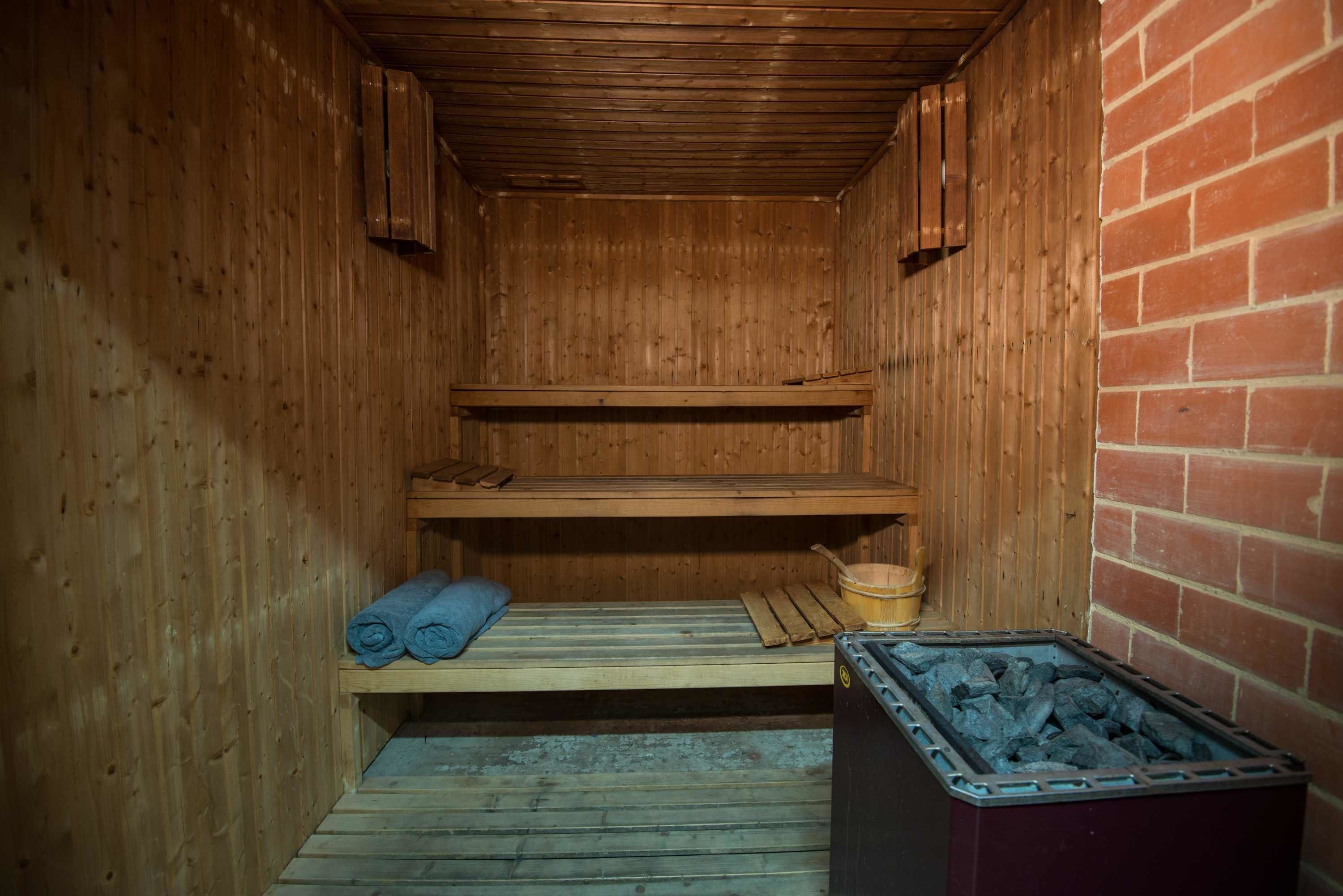 A sauna with wooden walls, a brick wall, and a charcoal bin.