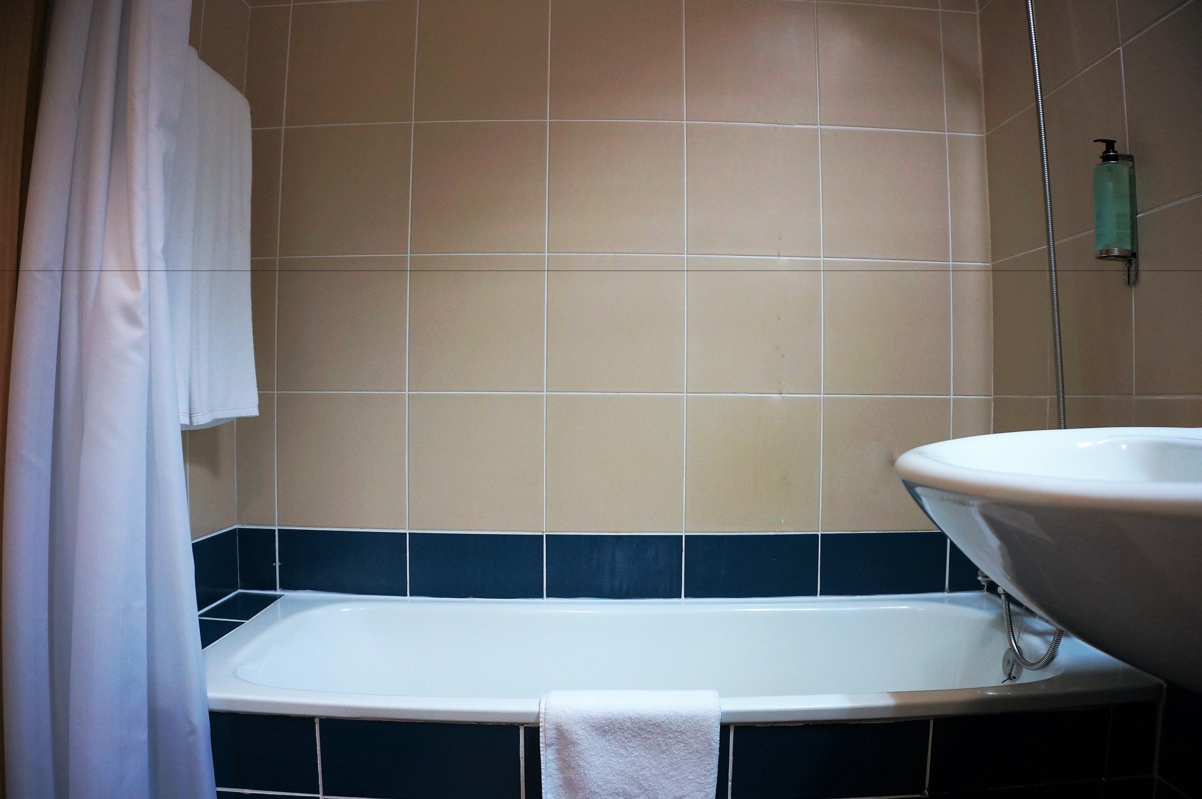 A bathroom with a bathtub, a white sink, and a showerhead.