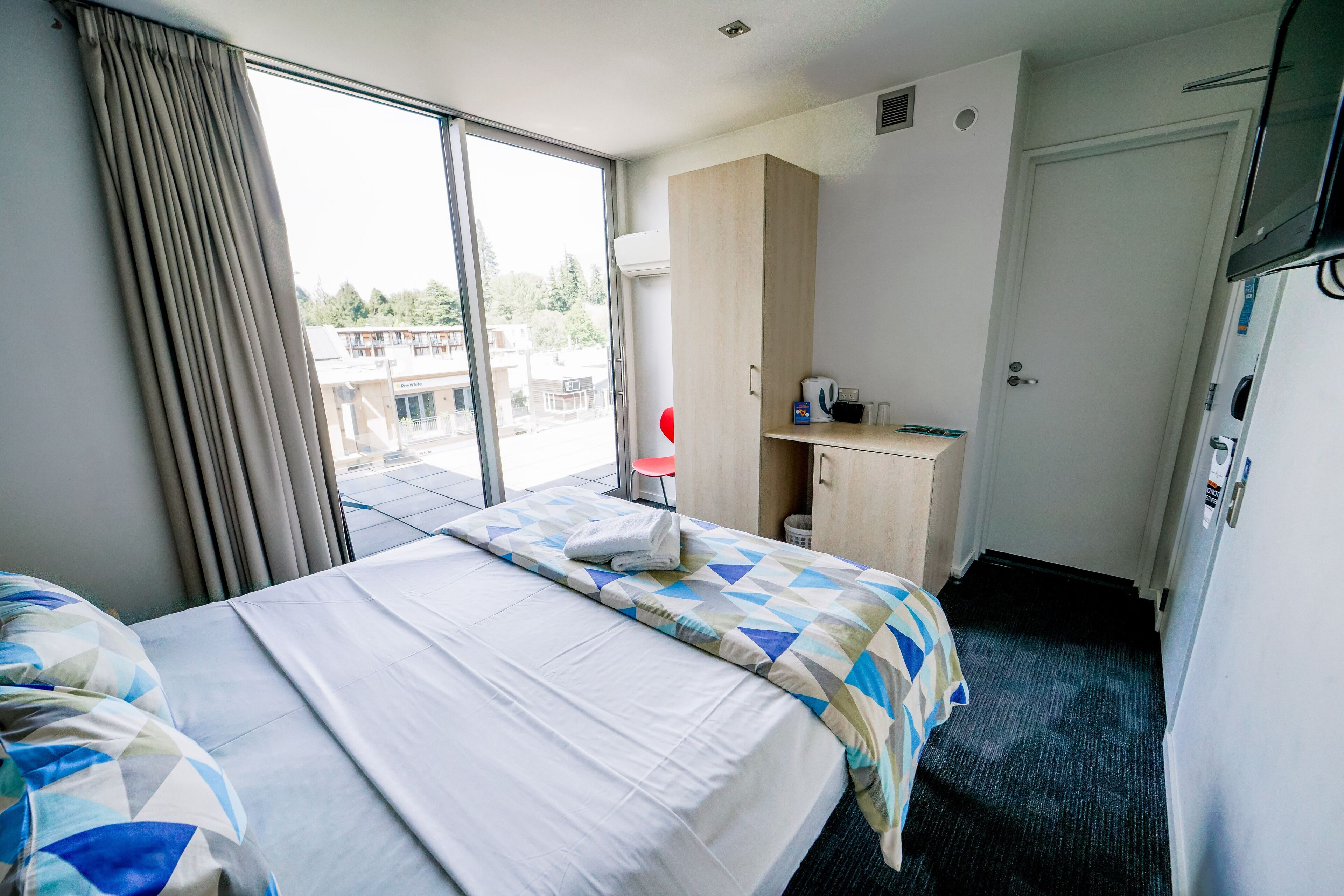 Ein Hotelzimmer mit Bett, Schreibtisch, Stuhl und Fernseher.