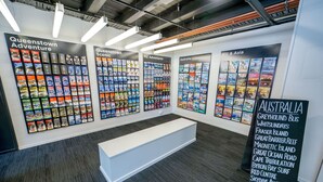 A travel agency wall with brochures for Queenstown, NZ, and Fiji & Asia. - Nomads Queenstown Backpackers (Queenstown)